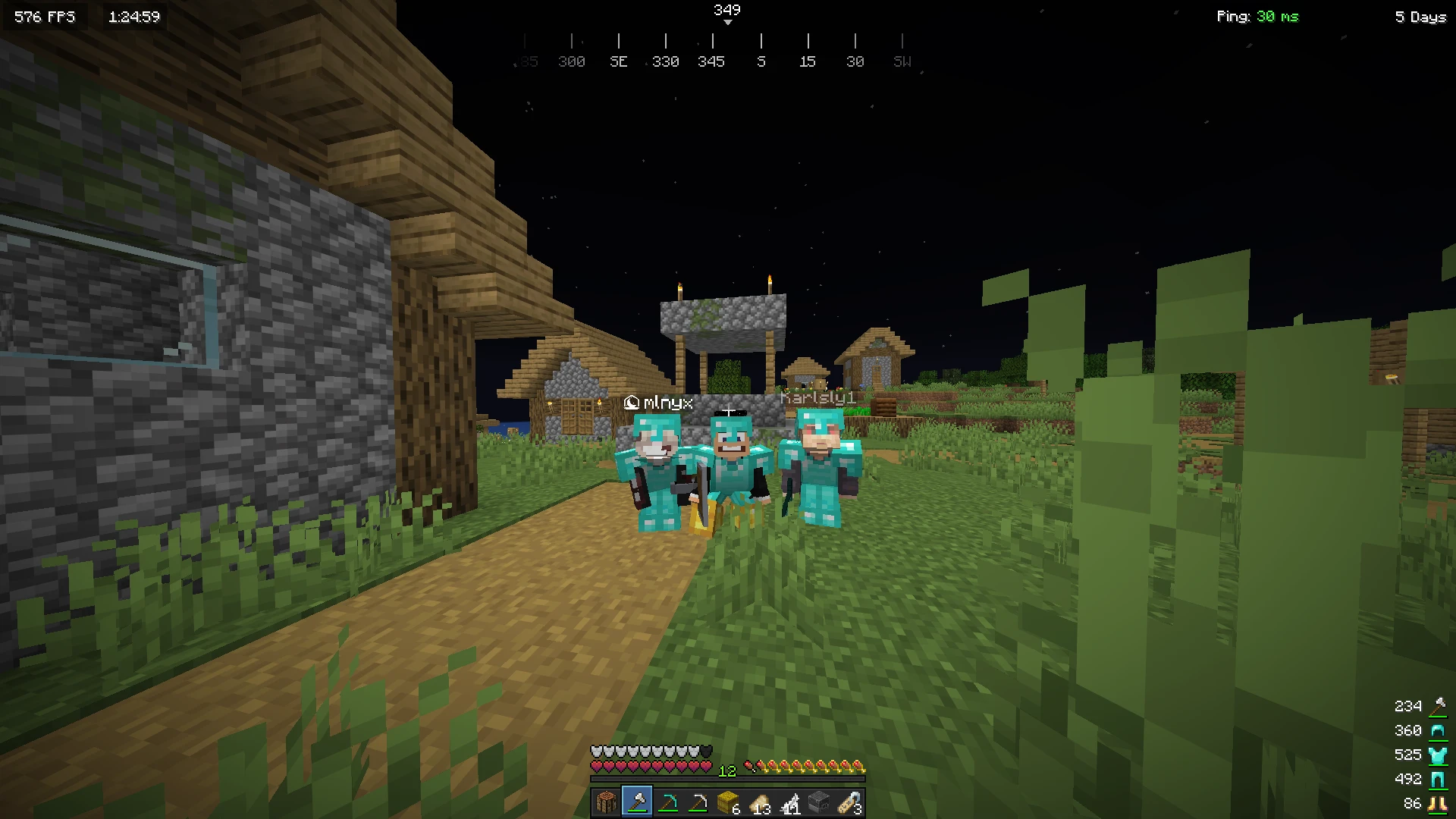 Three players in diamond armor at a village by night